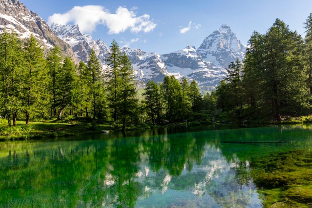 Stunning view of Lago Blu with the Alps and lush fir trees in Breuil-Cervinia, Italy.